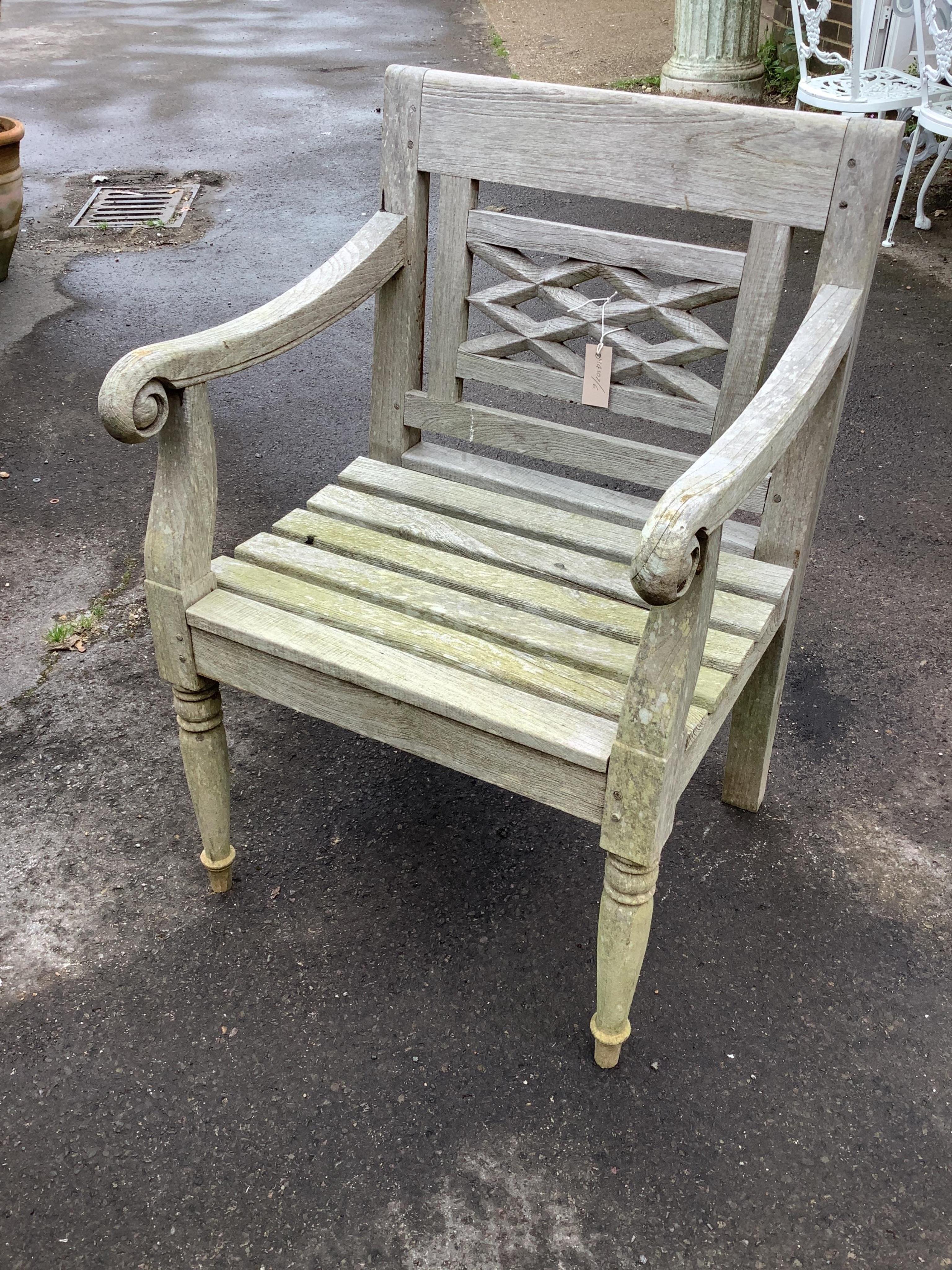 A circular weathered teak garden table, width diameter 150cm, height 73cm and four elbow chairs